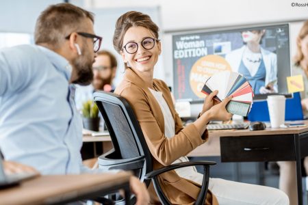 Grafik-/Webdesigner*in und Mediengestalter*in sitzen an einem Schreibtisch und unterhalten sich